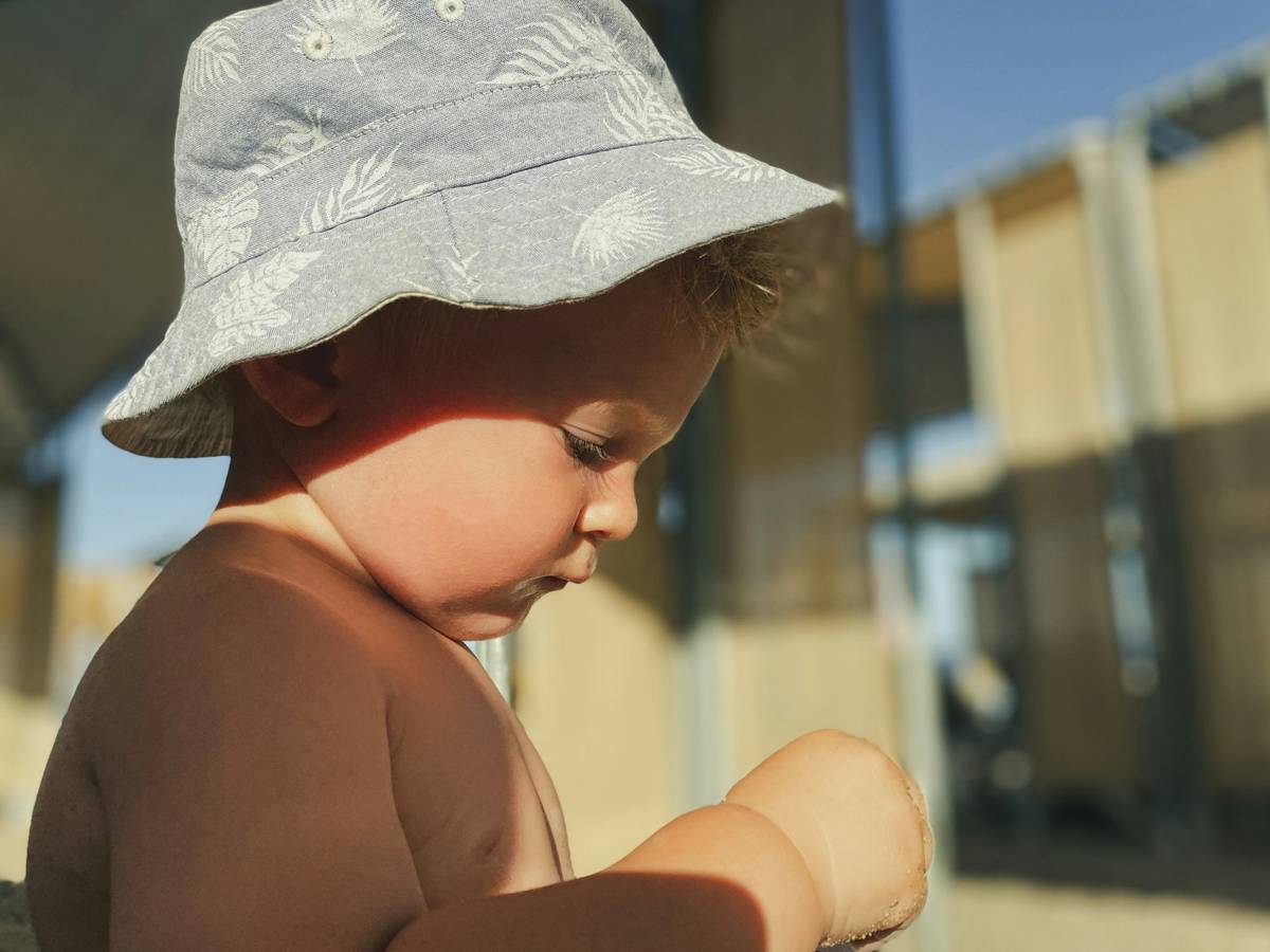 Baby wearing sun hat and non-toxic sunscreen during outdoor play — sun protection baby sunscreen can i apply correctly